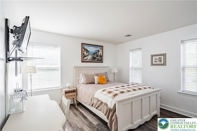 bedroom with dark wood-type flooring, multiple windows, and baseboards
