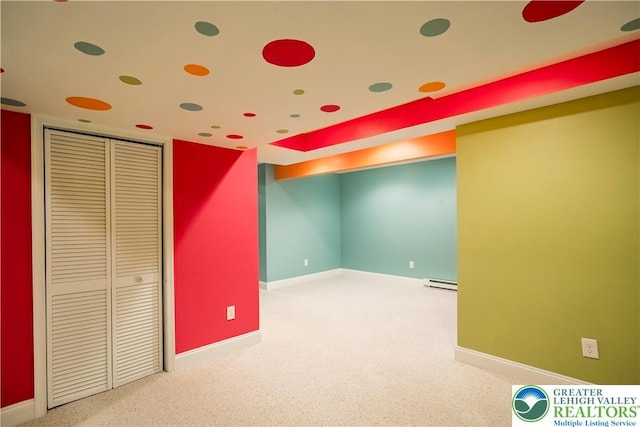 unfurnished bedroom with baseboard heating, carpet flooring, and baseboards
