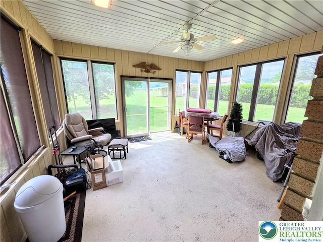 sunroom with a ceiling fan and wooden walls