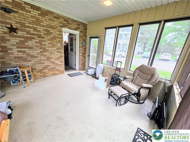 sunroom featuring brick wall