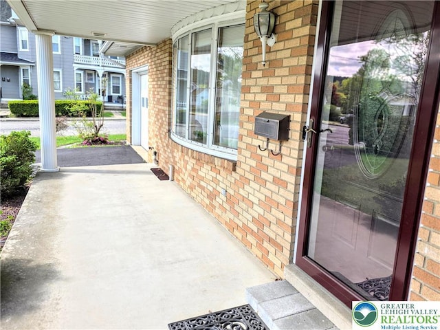 doorway to property with a porch and brick siding