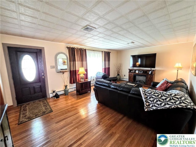 living area featuring wood-type flooring, a baseboard heating unit, and baseboards