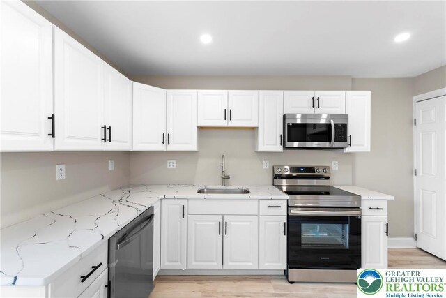 410 E Hamilton St, Allentown City, PA 18109 - kitchen with appliances with stainless steel finishes, a sink, white cabinets, light stone countertops, and light wood-style floors