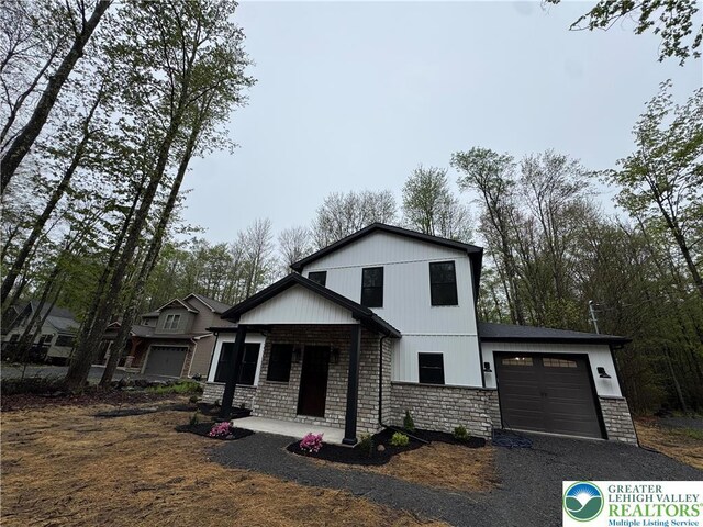 211 Maxatawny Dr, Coolbaugh Twp, PA 18347 - view of front of house with a garage, a porch, driveway, and stone siding