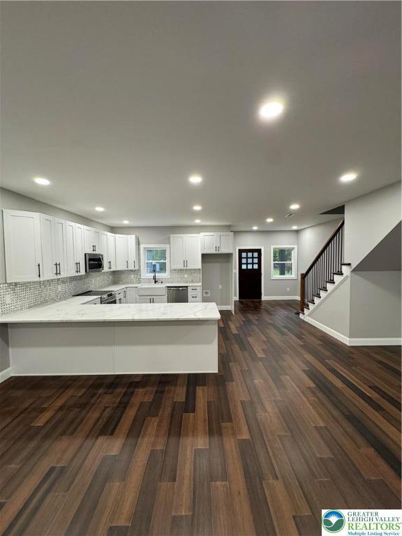 211 Maxatawny Dr, Coolbaugh Twp, PA 18347 - kitchen featuring appliances with stainless steel finishes, a peninsula, white cabinetry, recessed lighting, and dark wood-type flooring