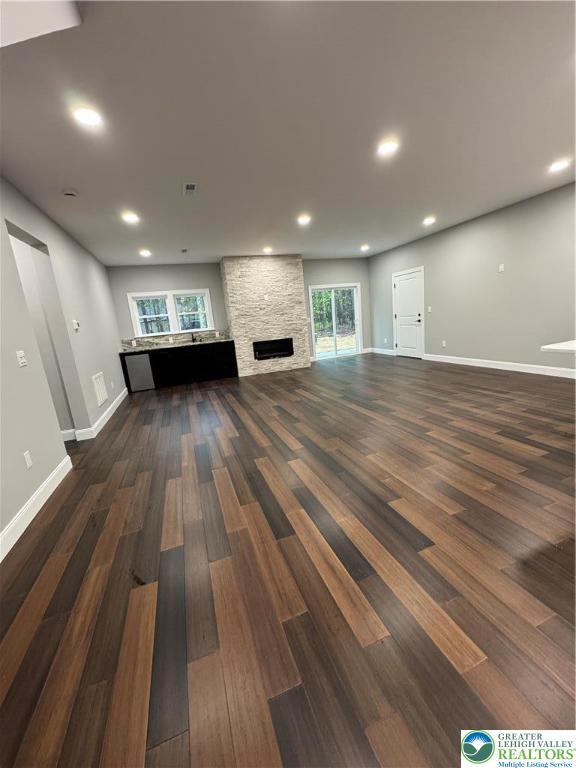 211 Maxatawny Dr, Coolbaugh Twp, PA 18347 - unfurnished living room with dark wood-style flooring, baseboards, a stone fireplace, and recessed lighting