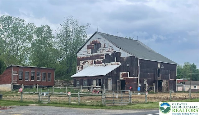 view of front of property with a barn, fence, an outbuilding, and a gate