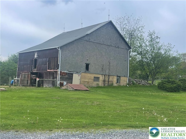view of home's exterior with a lawn and an outbuilding