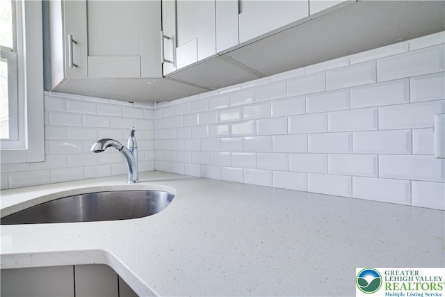 1918 Horseshoe, Coolbaugh Twp, PA 18466 - kitchen featuring a sink, backsplash, light stone countertops, and white cabinetry