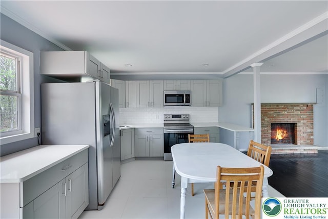 1918 Horseshoe, Coolbaugh Twp, PA 18466 - kitchen featuring appliances with stainless steel finishes, gray cabinets, a brick fireplace, backsplash, and light countertops