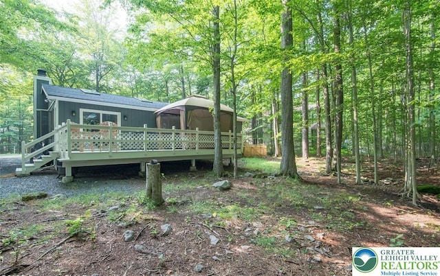 266 Maxatawny Dr, Coolbaugh Twp, PA 18347 - rear view of property with a wooden deck, a chimney, and a forest view