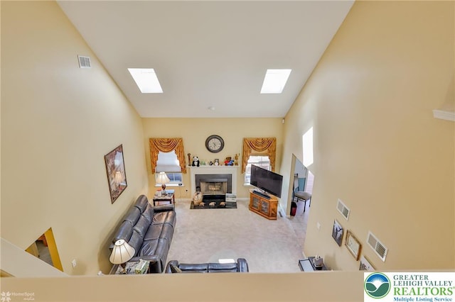 carpeted living area with a skylight and a fireplace