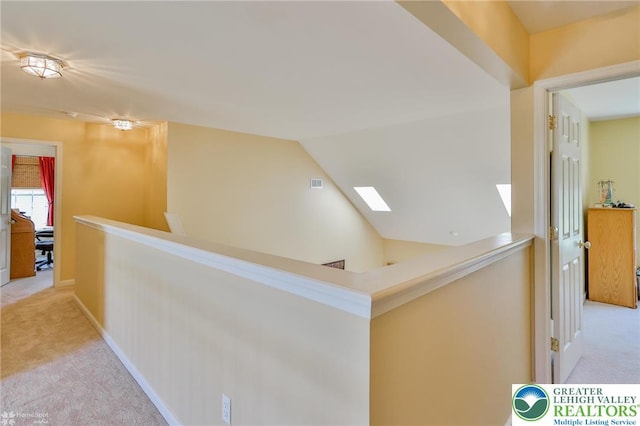 hall with light carpet, an upstairs landing, lofted ceiling, and baseboards