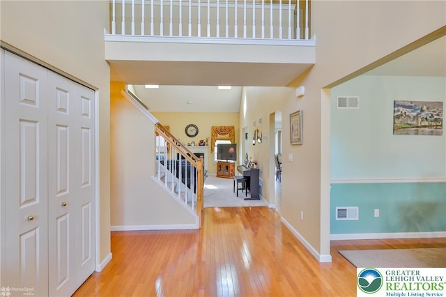 entrance foyer featuring a high ceiling, hardwood / wood-style floors, stairway, and baseboards