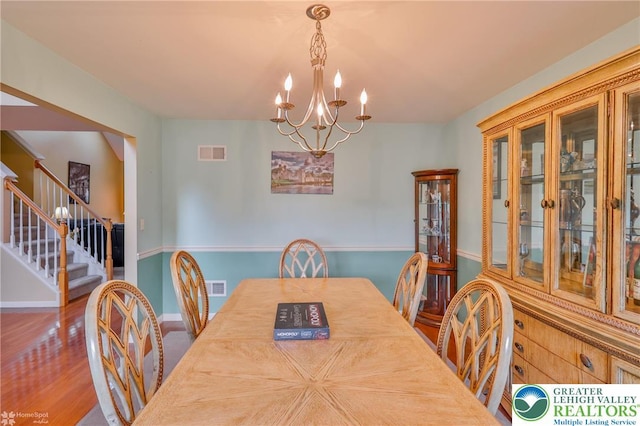 dining area featuring a chandelier, stairs, wood finished floors, and baseboards