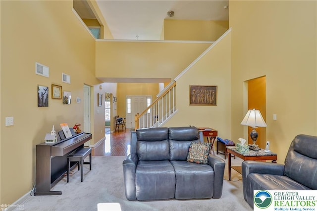 living area featuring stairs, a towering ceiling, wood finished floors, and baseboards