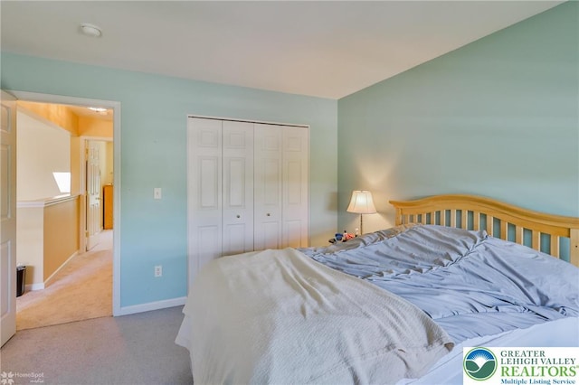 carpeted bedroom with a closet and baseboards