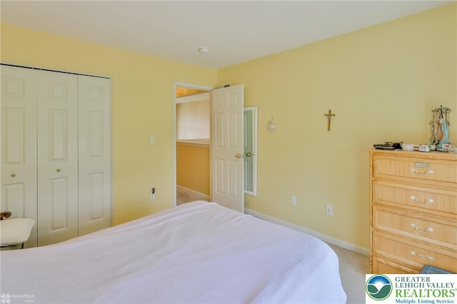 bedroom with a closet, baseboards, and light colored carpet
