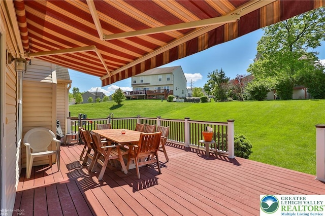 wooden deck with outdoor dining area and a lawn