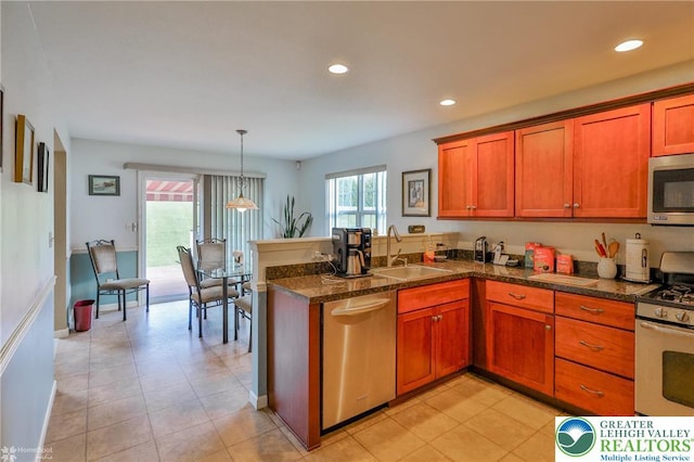 kitchen with a sink, stainless steel appliances, a peninsula, brown cabinetry, and recessed lighting