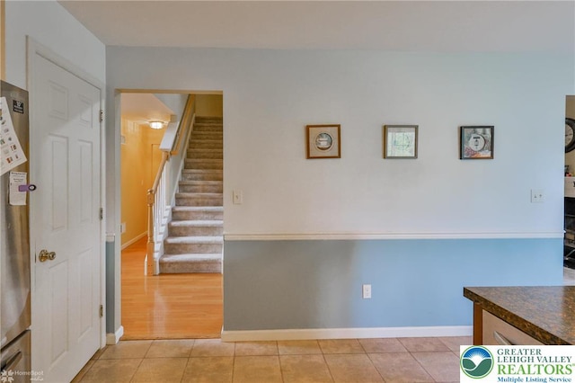 stairway with tile patterned floors and baseboards
