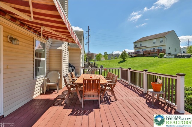 wooden deck with outdoor dining space and a yard