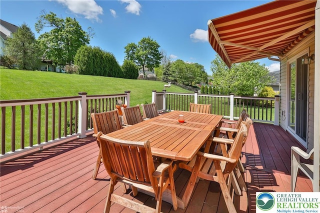 deck with outdoor dining area and a yard