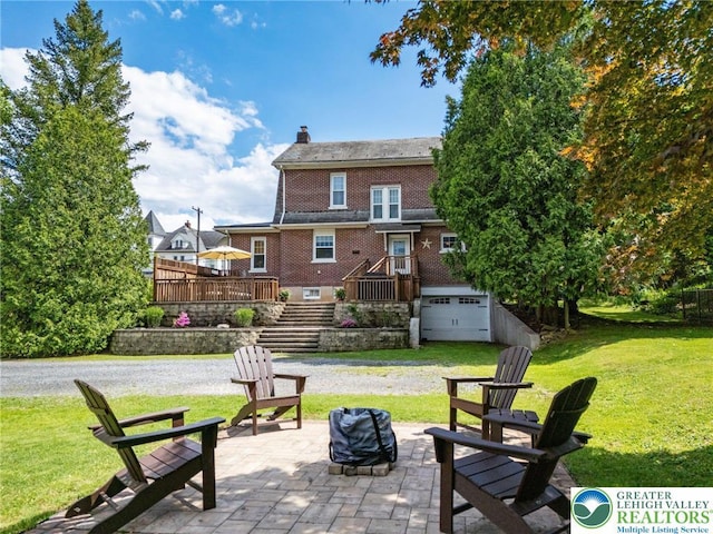 rear view of property with a fire pit, a chimney, stairway, a yard, and brick siding