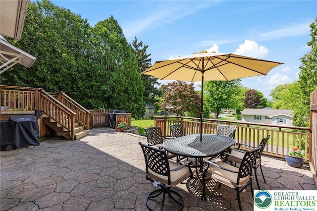view of patio featuring outdoor dining area, fence, and stairs
