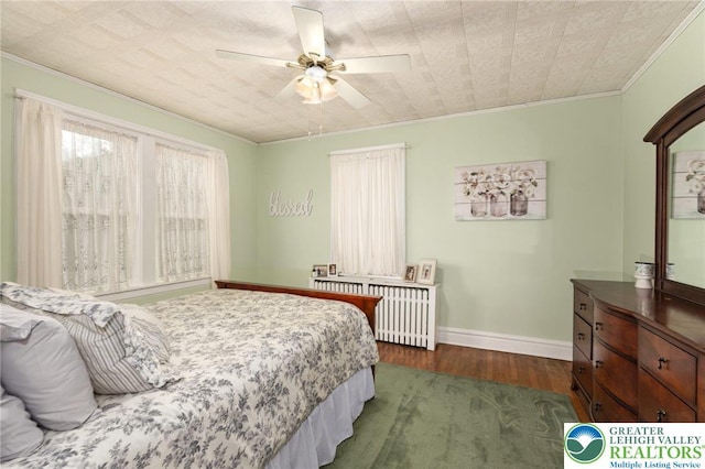 bedroom featuring ornamental molding, dark wood-style flooring, baseboards, a ceiling fan, and radiator