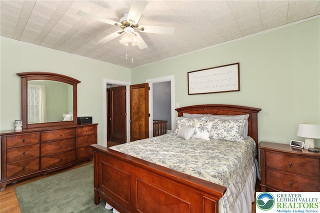bedroom with wood finished floors, ornamental molding, and ceiling fan