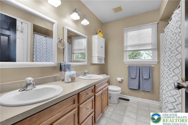 full bath featuring toilet, double vanity, baseboards, and tile patterned floors