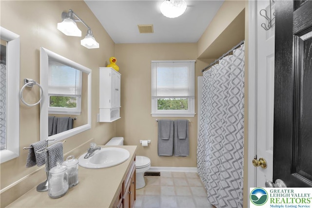 full bathroom with healthy amount of natural light, toilet, vanity, and baseboards