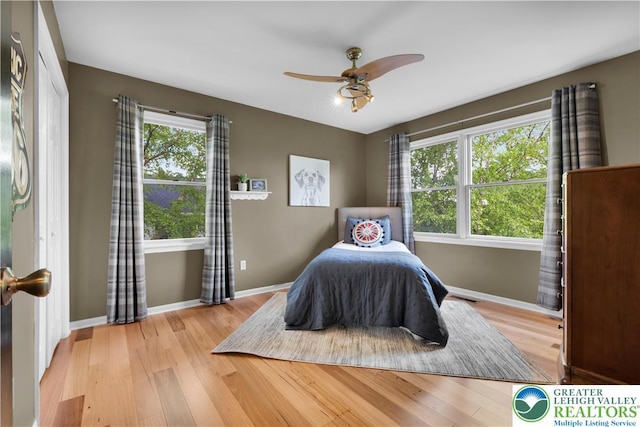 bedroom with light wood-style flooring, baseboards, and a ceiling fan