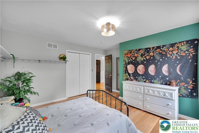 bedroom with wood finished floors, baseboards, and a closet