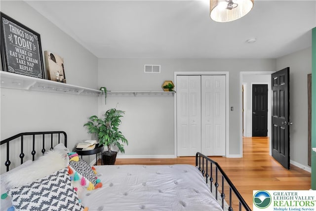 bedroom with wood finished floors, a closet, and baseboards