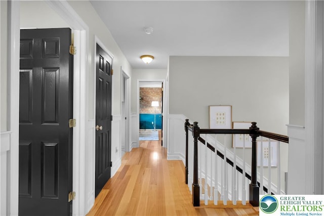 corridor with an upstairs landing and light wood-style floors