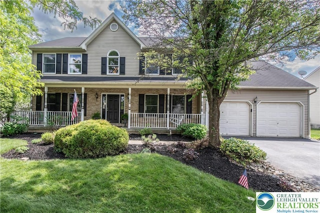view of front of home featuring covered porch, driveway, an attached garage, and a front lawn