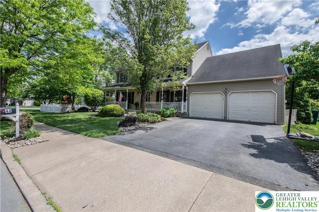 view of front of property with asphalt driveway, covered porch, a garage, and a front lawn