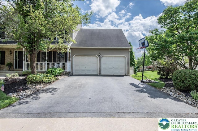 view of front of property featuring driveway, a garage, a porch, and fence