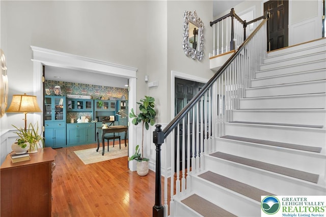 stairway with wood finished floors and a towering ceiling
