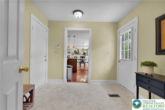 carpeted foyer entrance featuring baseboards
