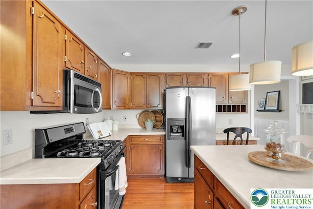 kitchen featuring stainless steel appliances, brown cabinets, light wood finished floors, light countertops, and recessed lighting