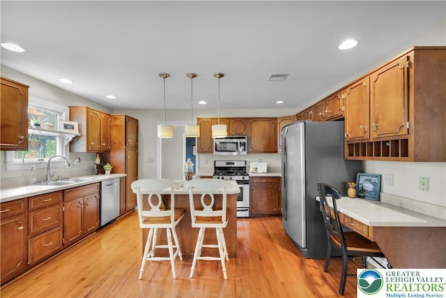 kitchen featuring stainless steel appliances, a sink, a breakfast bar, light wood-style floors, and a kitchen island