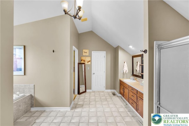 bathroom featuring lofted ceiling, a chandelier, vanity, a garden tub, and baseboards
