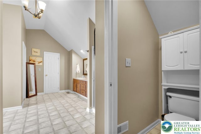 bathroom featuring vaulted ceiling, a chandelier, vanity, toilet, and baseboards