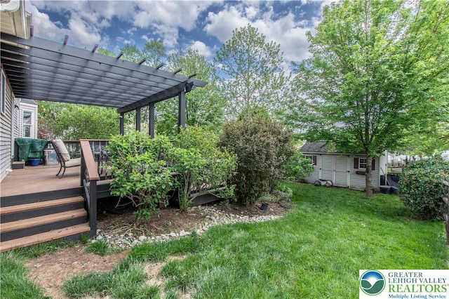 view of grassy yard with a wooden deck, a pergola, and an outdoor structure