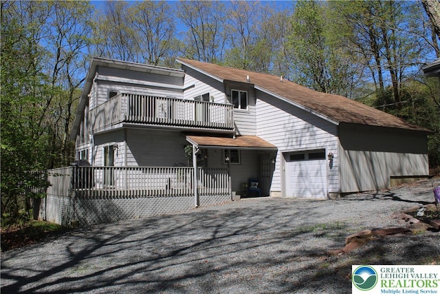 view of front of property featuring a balcony, an attached garage, and driveway