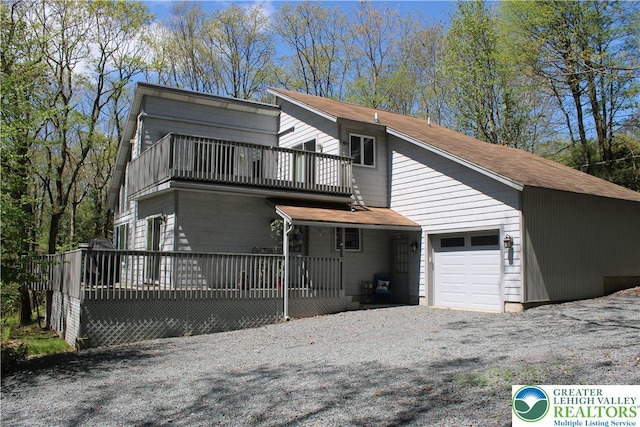 view of front of property with a balcony, an attached garage, driveway, and a shingled roof