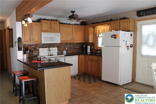 kitchen featuring white appliances, a peninsula, a ceiling fan, backsplash, and a sink